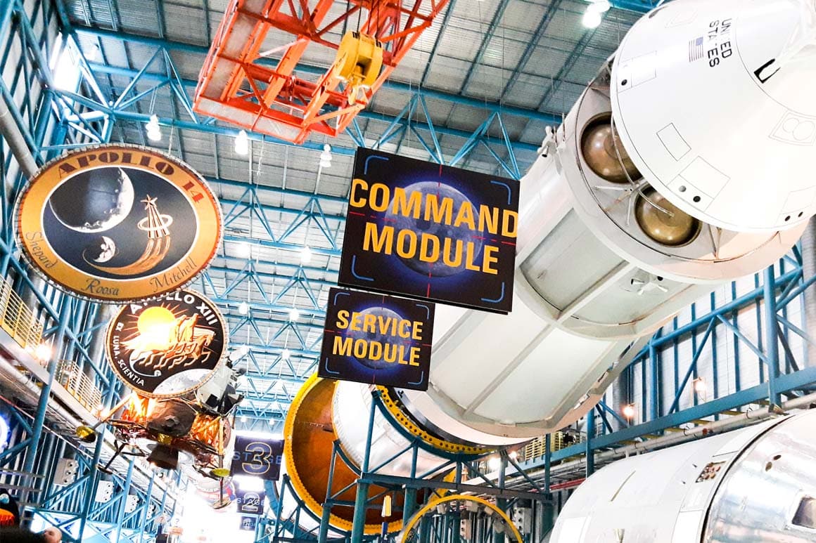 Apollo/Saturn V Center no Kennedy Space Center: enorme foguete Saturn V suspenso horizontalmente, único em exibição completa, com estágios separados mostrando sua escala monumental.