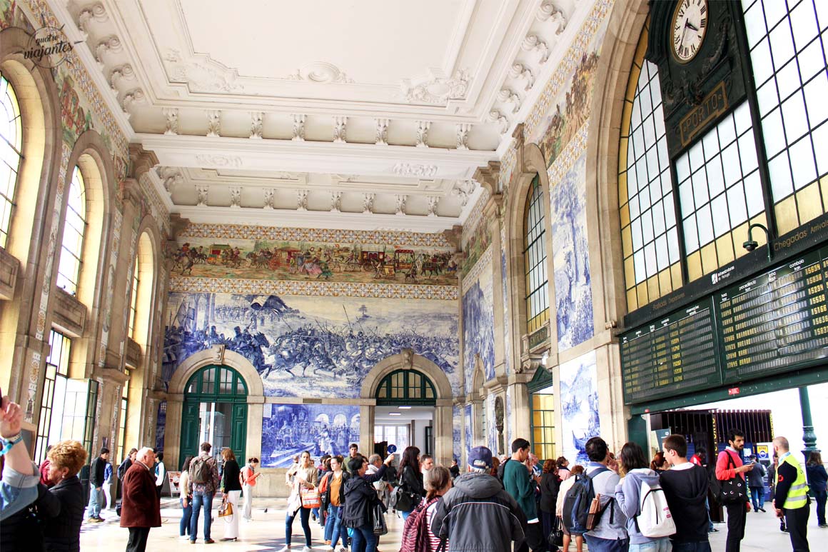 Interior da Estação São Bento no Porto com paredes cobertas por painéis de azulejos azuis retratando cenas históricas portuguesas