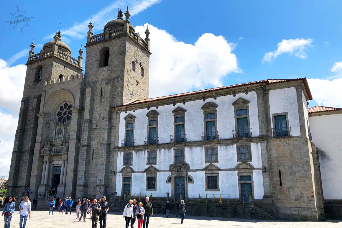 Fachada românica da Sé Catedral do Porto com portão ornamentado e céu azul claro em dia ensolarado