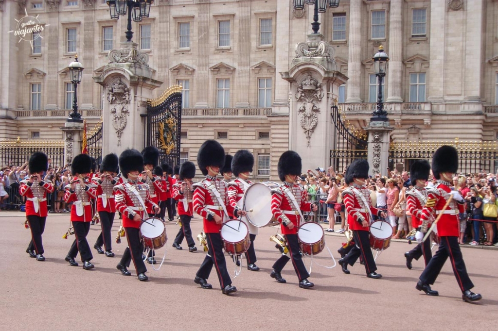 Desfile da Troca da Guarda no Palácio de Buckingham, Londres: soldados da Guarda Real em uniformes vermelhos e chapéus de urso marcham com banda militar