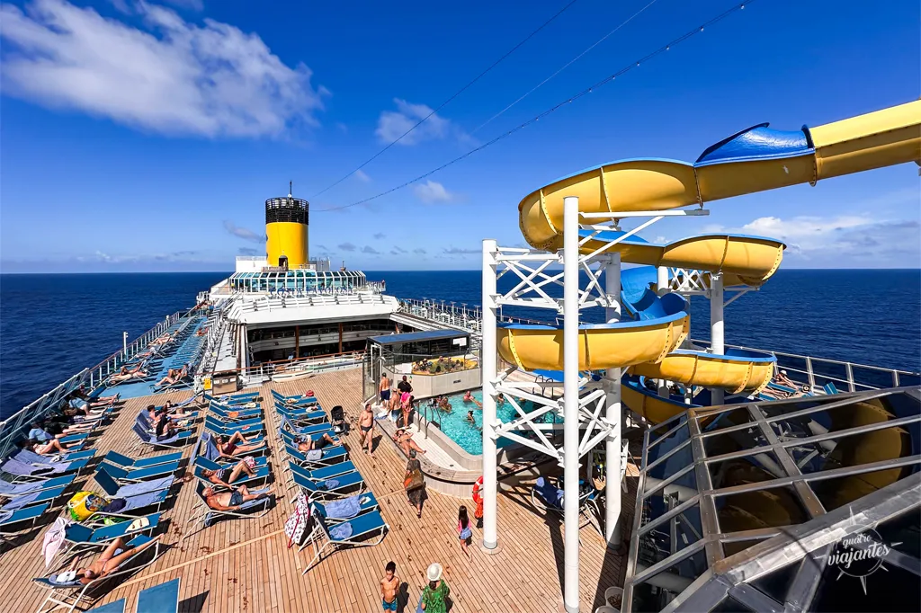 último andar do navio Costa Favolosa, com piscina, tobogã amarelo e espreguiçadeiras azuis
