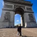 Arco do Triunfo Paris Champs-Élysées: fachada neoclássica com baixos-relevos esculturas Vitória e pedestres casal selfie em praça pavimentada céu azul