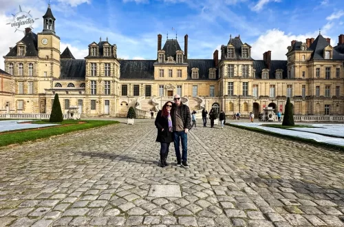 Castelo de Fontainebleau França, casal viaja pelo pátio principal em dia ensolarado