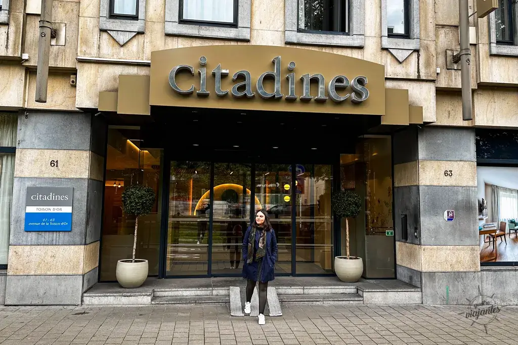 Mulher na entrada Citadines Apart’hotel Toison d'Or Bruxelas, fachada amarela moderna com plantas e portas de vidro.