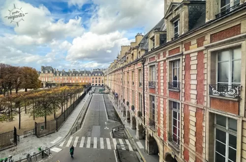 Place des Vosges Paris França, edifícios rosa clássicos outono com pedestres na rua arborizada. ​