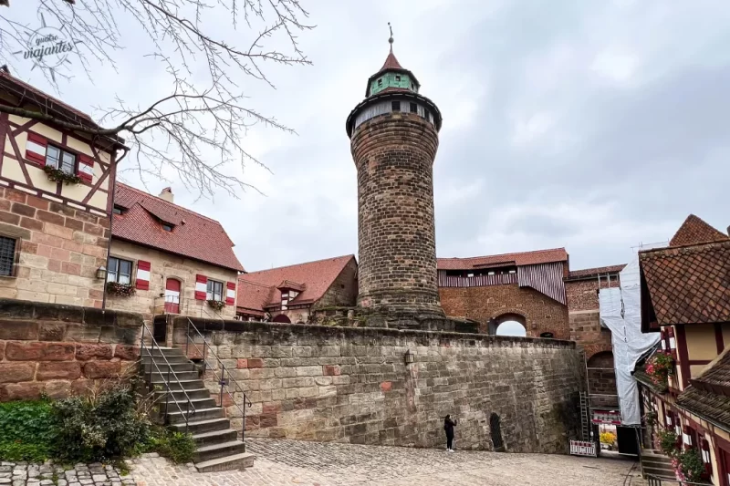 "Torre Sinwell (Sinwellturm) no Castelo Imperial de Nuremberg, Alemanha. Vista da torre medieval de pedra com arquitetura enxaimel e telhados de cerâmica sob céu nublado."
